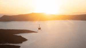 Helicopter flying over Santorini caldera at sunset with panoramic views of the Aegean Sea