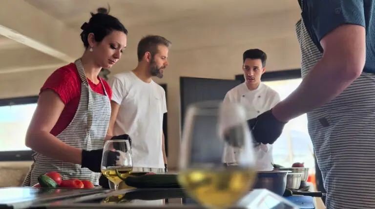 Glasses of white wine on the worktop as guests cook with the chef during a Santorini cooking class and wine pairing