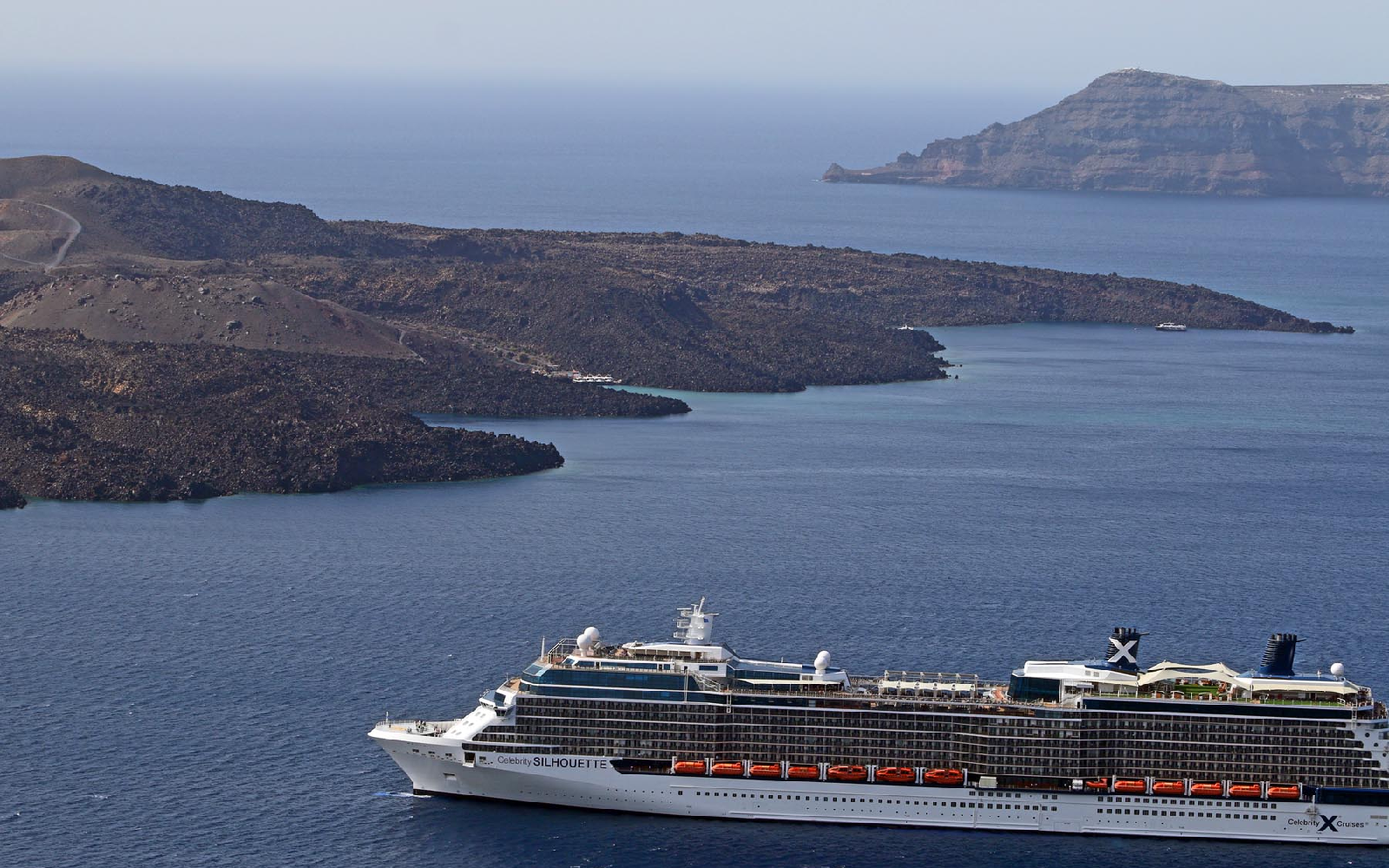 Santorini Day Tour: Cruise Ship Arrival A large cruise ship sails past the volcanic coastline of Santorini, Greece.