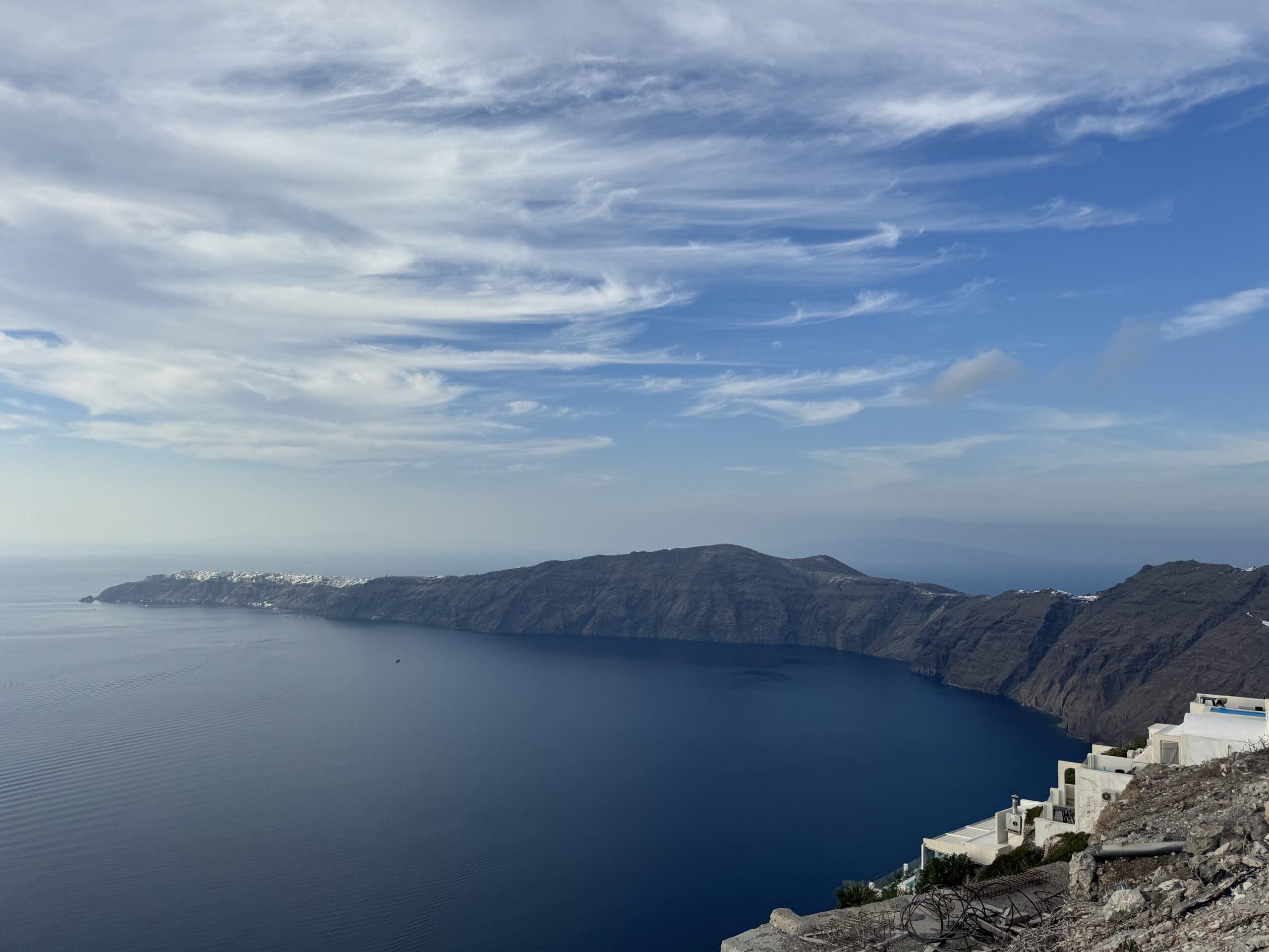 Santorini Caldera Vista A panoramic view of the Santorini caldera, showcasing the deep blue Aegean Sea, volcanic cliffs, and white-washed buildings nestled on the edge.