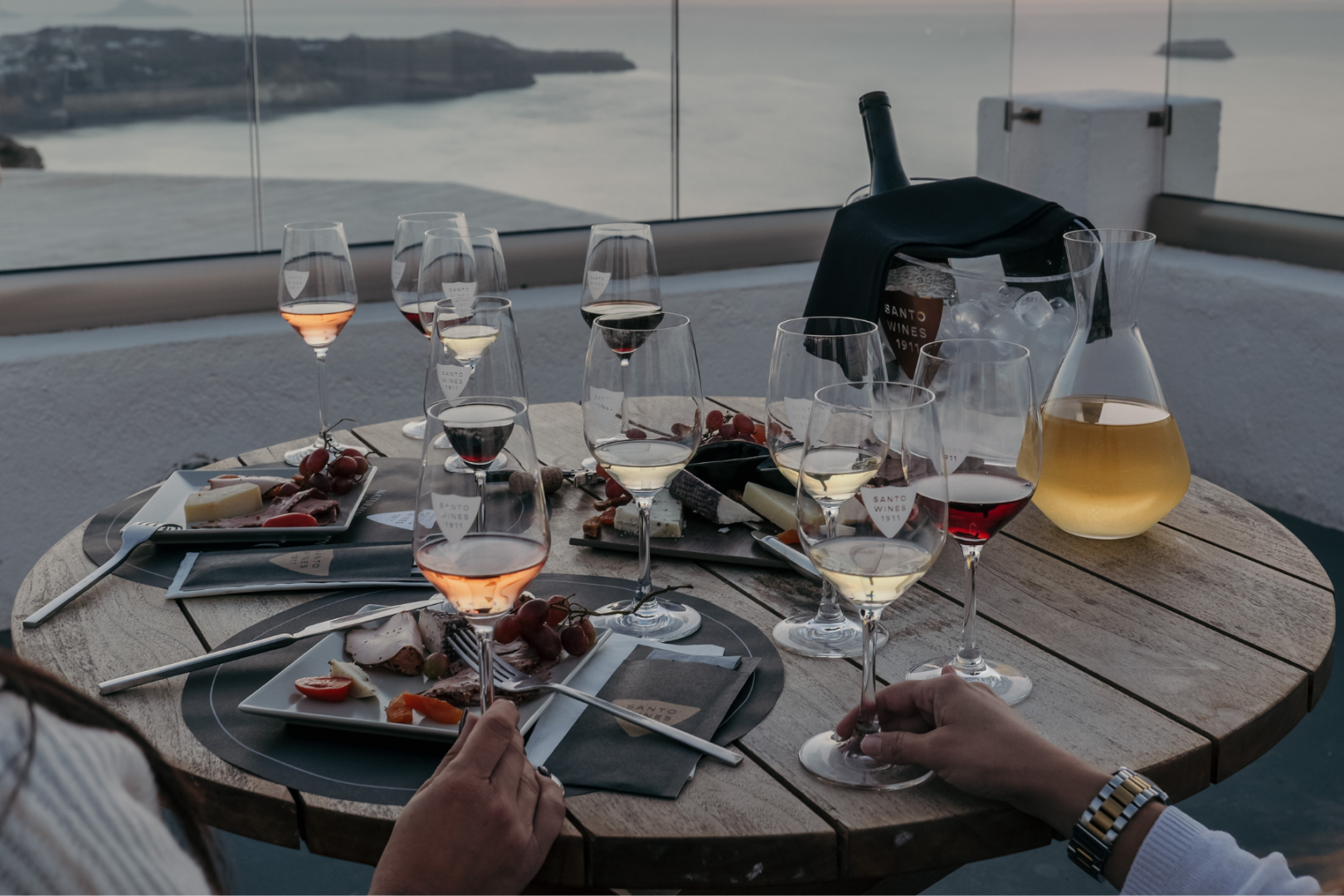 Wine & Food Pairing at Santo Wines – Santorini Sunset Dinner Santo Wines tasting table with local wines and food pairings at sunset, Santorini