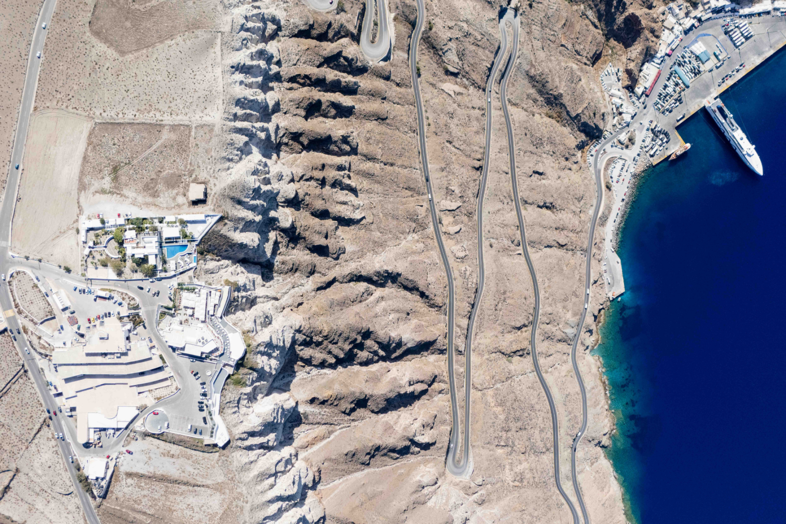 Santorini Caldera & Port from Above – Private Island Tour Aerial view of Santorini's caldera cliffs and Athinios port