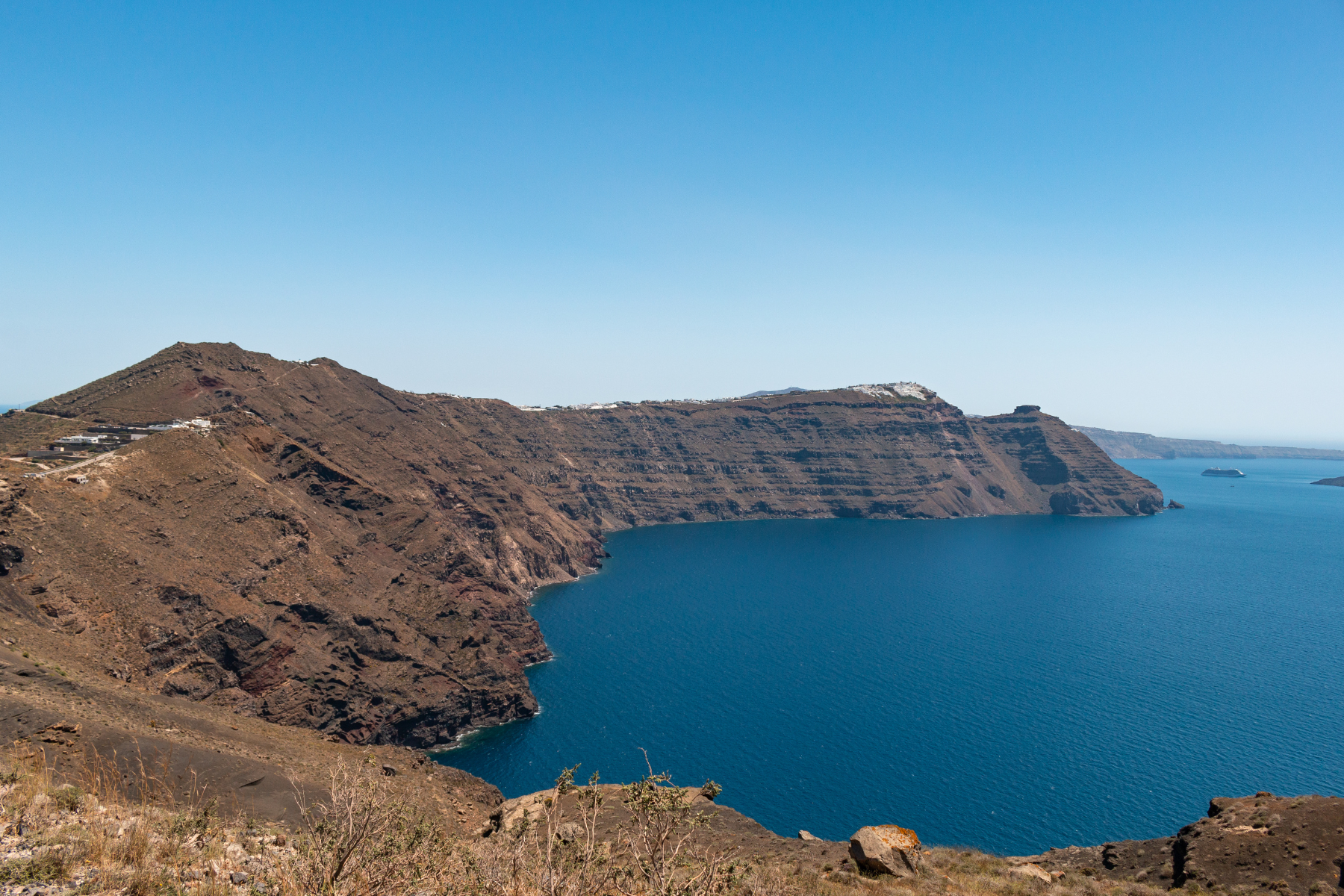 View of Santorini’s caldera cliffs and deep blue Aegean Sea on a clear day—an iconic landscape for travelers seeking the best things to do on Santorini and top Santorini activities.
