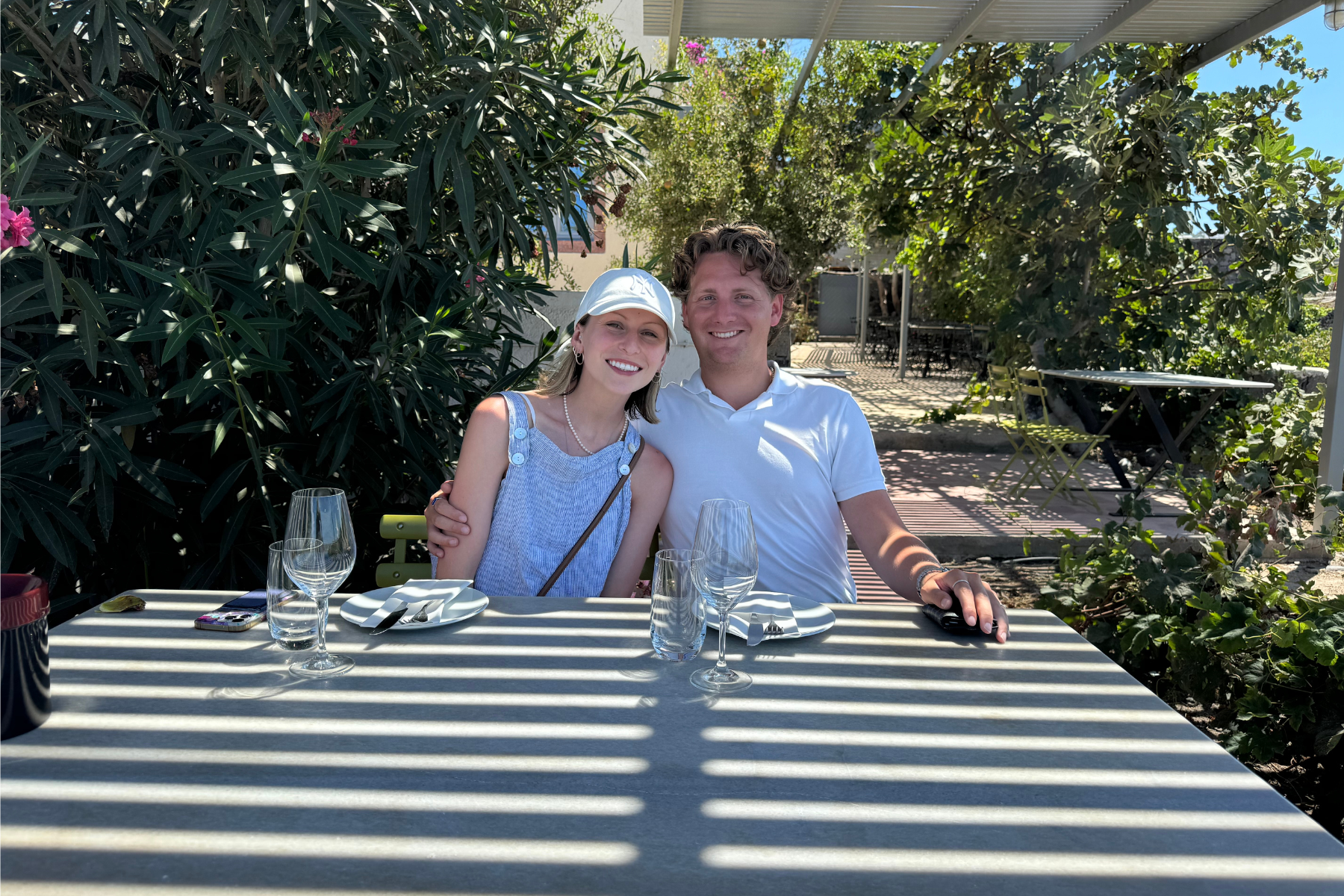 Santorini Private Wine Tour Two people enjoy a wine tasting at a sunny Santorini vineyard during a private wine tour in Santorini