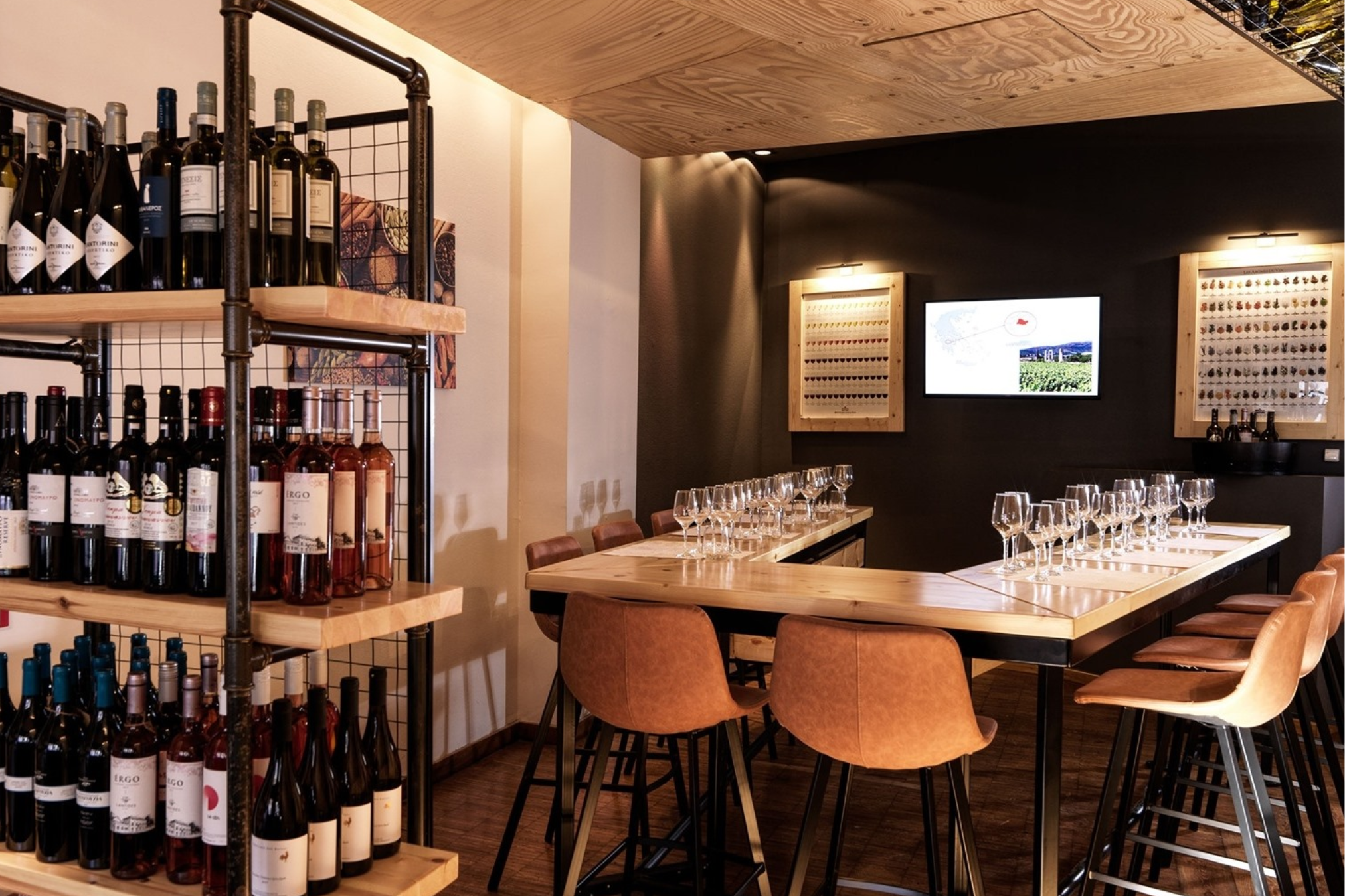 Wine Tasting Setup An indoor wine tasting area is arranged with wine bottles displayed on industrial-style shelves, and tasting glasses neatly lined up on a light wood bar with modern brown bar stools.