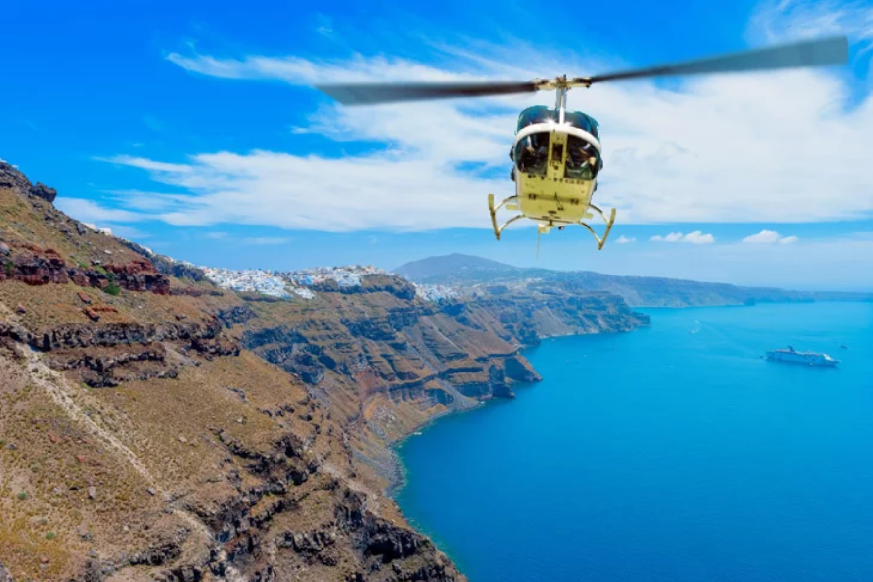 Helicopter Flying Over Coastal Cliffs and Blue Sea A helicopter flying above a coastal caldera, with rugged cliffs on one side and clear blue sea stretching below.