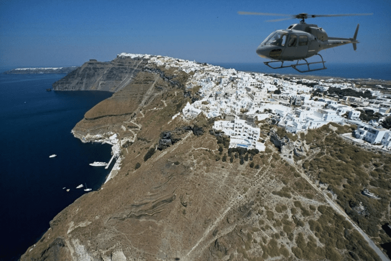 A helicopter flying above the Santorini caldera, with whitewashed cliffside villages overlooking the deep blue Aegean Sea.