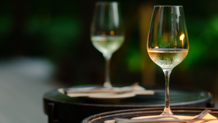 Glass of Assyrtiko white wine served outdoors in Santorini, reflecting the island’s historic wine culture and relaxed tasting experience