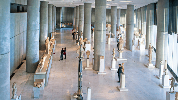 Interior of the Acropolis Museum in Athens with classical Greek statues displayed in a bright, modern gallery.