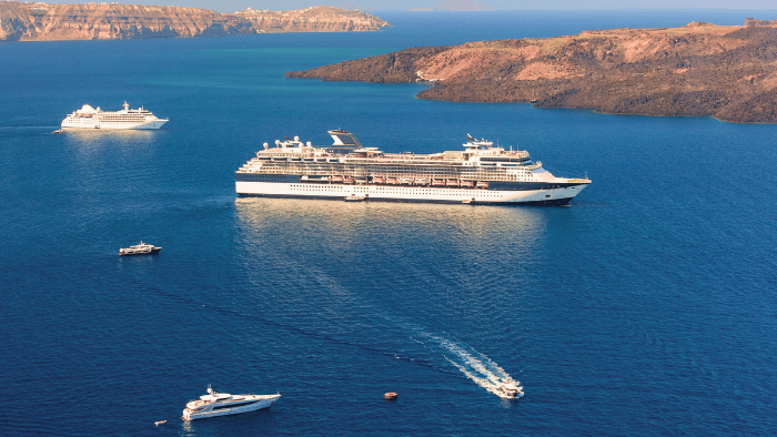 Cruise ships anchored in Santorini caldera near the cruise port, with tender boats transporting passengers to shore.