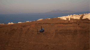 Helicopter flying above Santorini caldera cliffs near white villages with panoramic Aegean Sea views