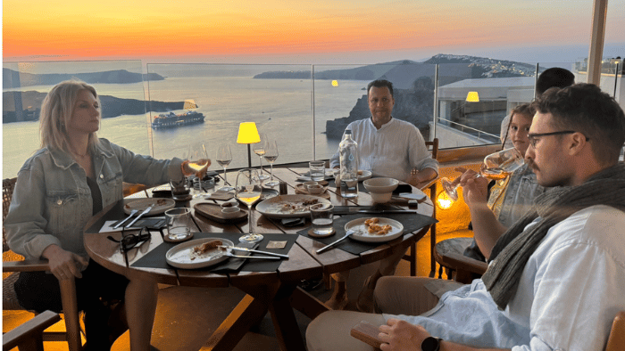 Group enjoying a private wine dinner with caldera sunset views in Santorini, a signature experience with Wineland Tours