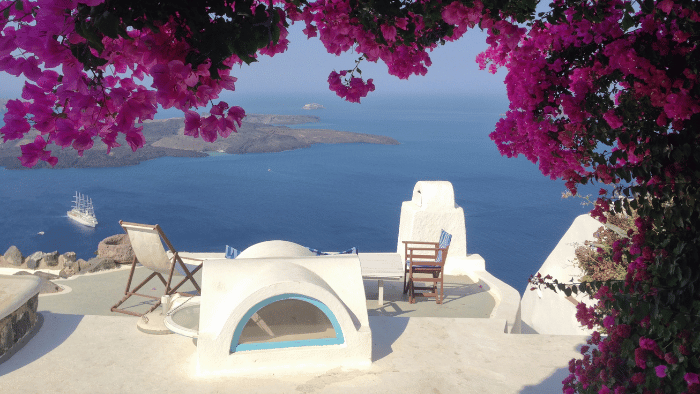 Santorini terrace framed by pink bougainvillea in spring, overlooking the caldera, one of the best times to visit the island
