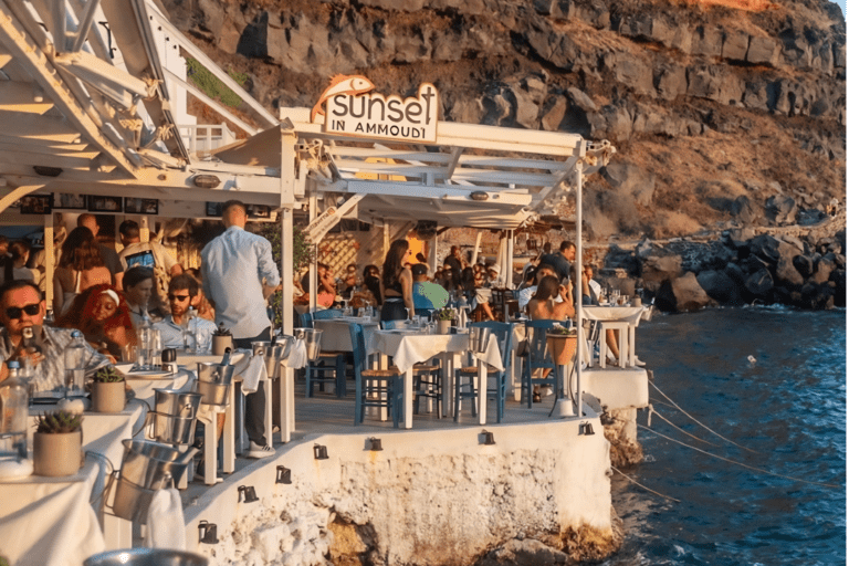 Seafront restaurant table set above crystal-clear waters in Ammoudi Bay