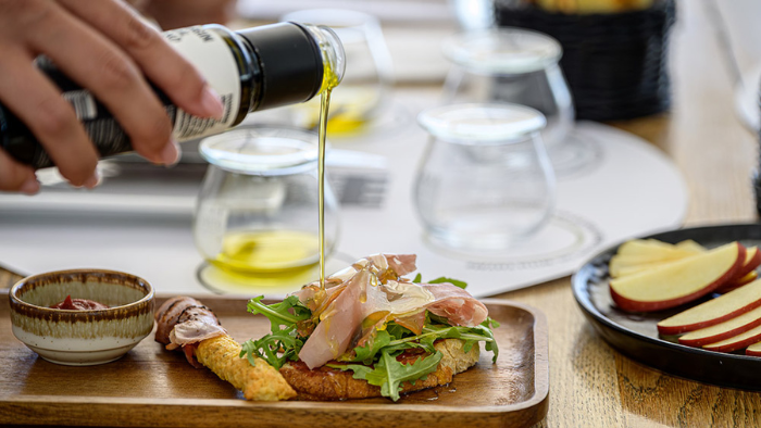 Extra virgin olive oil poured over Santorini bruschetta during a wine and olive oil tasting