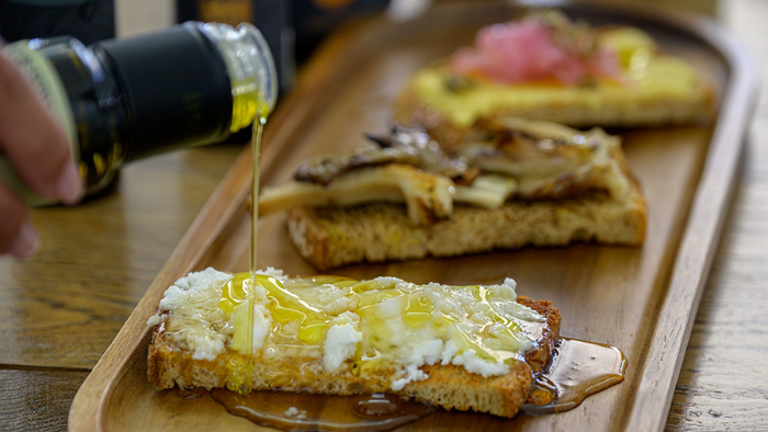 Greek bread topped with cheese and mushrooms drizzled with Santorini olive oil