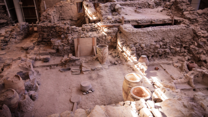 Akrotiri archaeological site ruins in Santorini with ancient stone walls and large storage jars