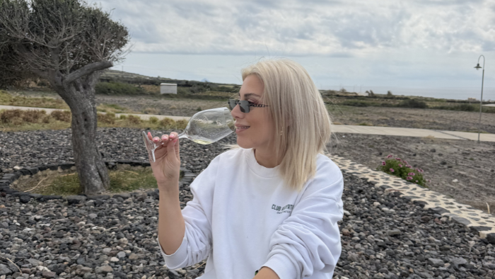 Tasting Assyrtiko white wine at a Santorini vineyard surrounded by volcanic stones