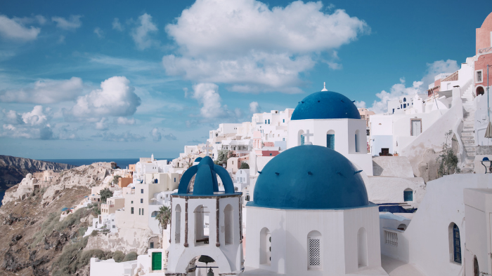 Blue-domed churches and whitewashed buildings in Oia village, Santorini, overlooking the caldera