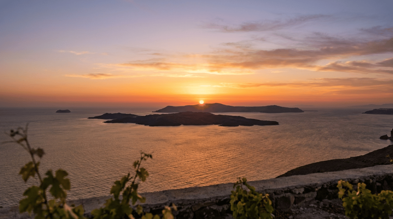 Sun setting over the Santorini caldera as the sky transitions from gold to pink, viewed from a cliffside vineyard terrace