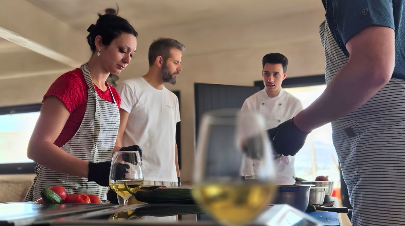 Glasses of white wine on the worktop as guests cook with the chef during a Santorini cooking class and wine pairing